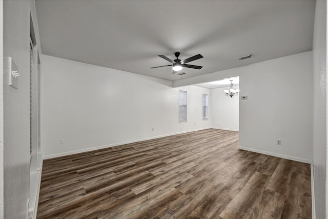 unfurnished room featuring ceiling fan with notable chandelier and dark wood-type flooring