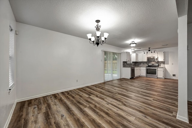 unfurnished living room with a notable chandelier, a textured ceiling, and dark hardwood / wood-style flooring