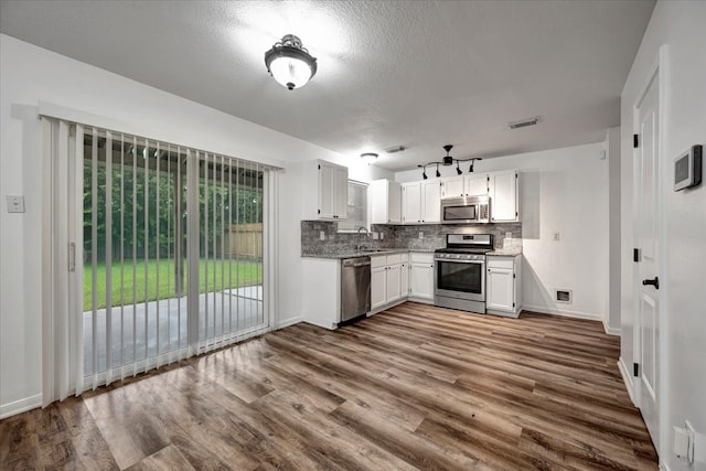 kitchen featuring white cabinets, appliances with stainless steel finishes, hardwood / wood-style floors, and tasteful backsplash