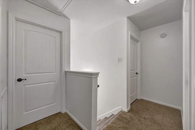 hallway with a textured ceiling and carpet flooring