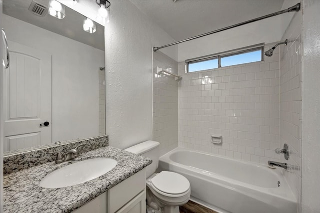 full bathroom with vanity, hardwood / wood-style floors, tiled shower / bath, and toilet