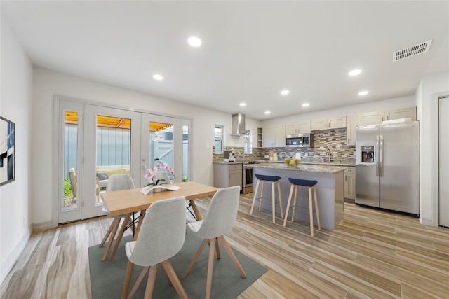 dining space featuring sink, french doors, and light hardwood / wood-style floors