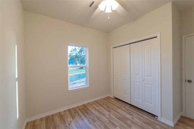 unfurnished bedroom featuring ceiling fan, light wood-style flooring, visible vents, baseboards, and a closet