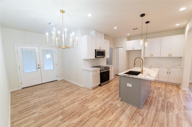 kitchen featuring appliances with stainless steel finishes, light wood-style flooring, a sink, and visible vents