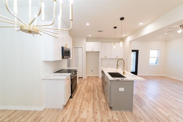 kitchen with stainless steel appliances, a sink, white cabinetry, and light wood-style floors