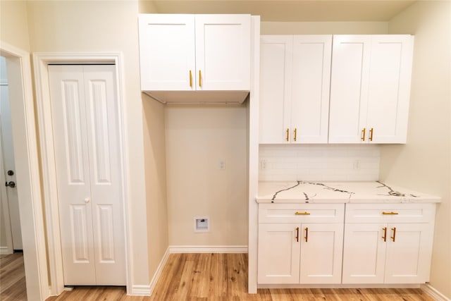 kitchen with light stone counters, white cabinets, light wood-style flooring, and decorative backsplash