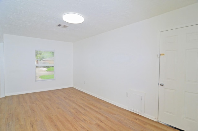 unfurnished room featuring light hardwood / wood-style floors and a textured ceiling