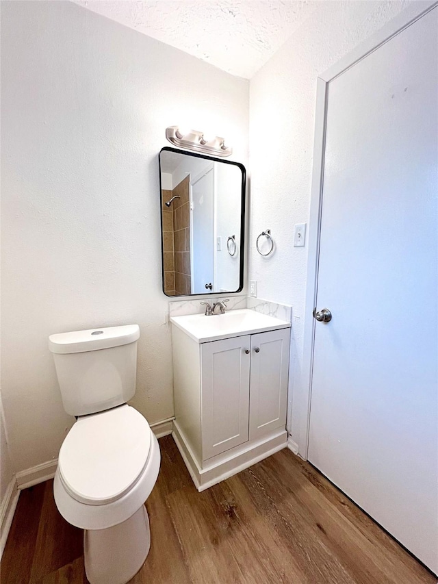 bathroom featuring hardwood / wood-style flooring, vanity, toilet, and a textured ceiling