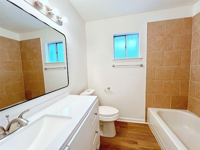 full bathroom with toilet, tiled shower / bath, a textured ceiling, vanity, and hardwood / wood-style flooring