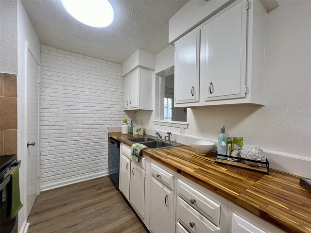 kitchen with wood counters, dishwasher, white cabinetry, and sink