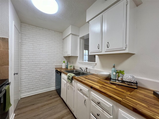 kitchen with sink, wooden counters, dishwasher, white cabinetry, and a textured ceiling