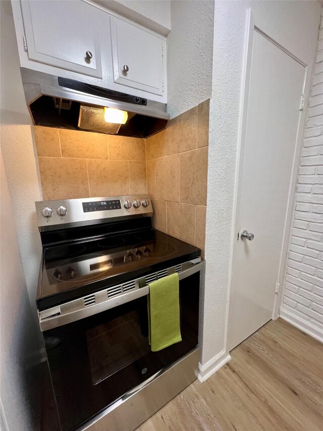 kitchen featuring backsplash, white cabinetry, stainless steel range with electric cooktop, and light hardwood / wood-style flooring