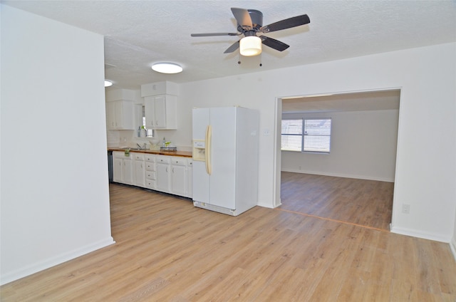 kitchen featuring white cabinets, light wood-type flooring, a textured ceiling, and white fridge with ice dispenser