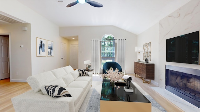 living room with a premium fireplace, light wood-type flooring, ceiling fan, and vaulted ceiling