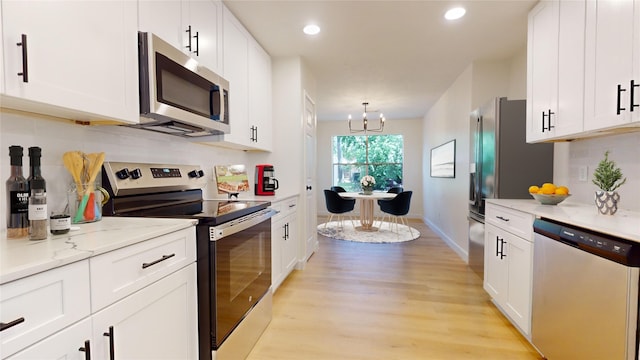 kitchen with stainless steel appliances, white cabinets, light wood-type flooring, light stone countertops, and backsplash