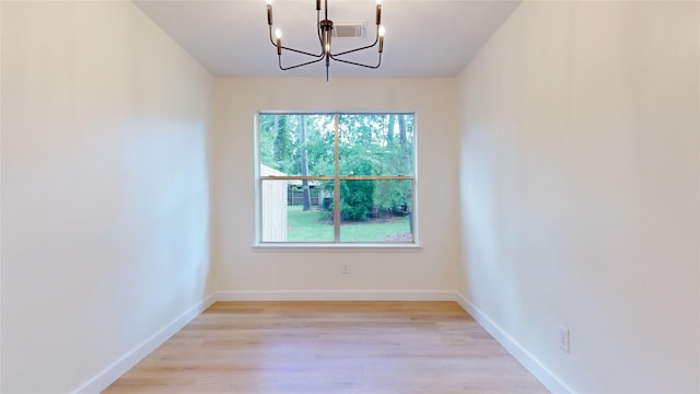 spare room with light hardwood / wood-style flooring and a chandelier