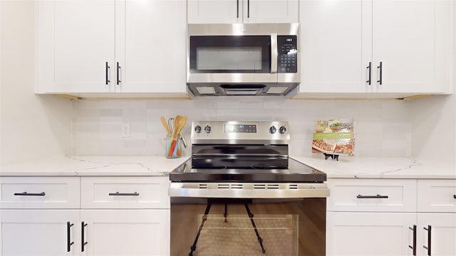 kitchen with stainless steel appliances, hardwood / wood-style floors, white cabinets, backsplash, and light stone countertops