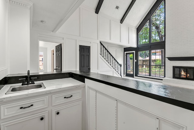 kitchen with a brick fireplace, sink, and white cabinets