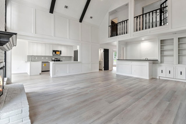 unfurnished living room with high vaulted ceiling, light hardwood / wood-style floors, and beamed ceiling