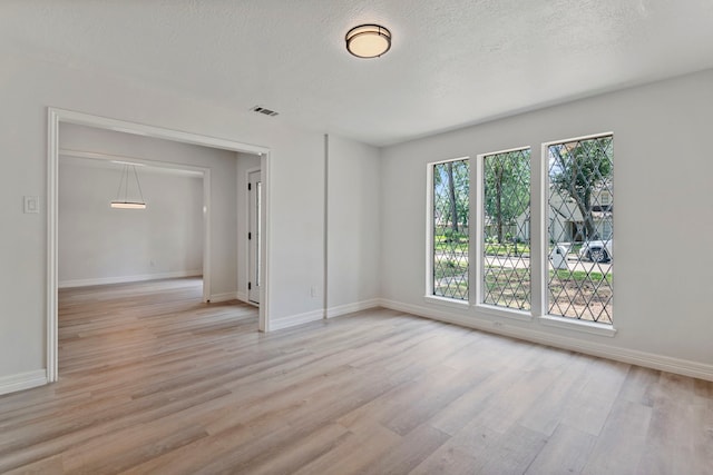 unfurnished room featuring a textured ceiling and light wood-type flooring