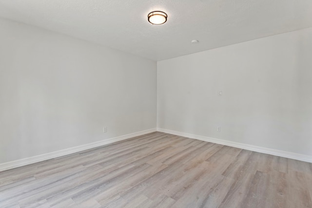 empty room with light hardwood / wood-style floors and a textured ceiling