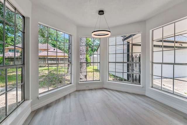 unfurnished dining area with wood-type flooring and a textured ceiling