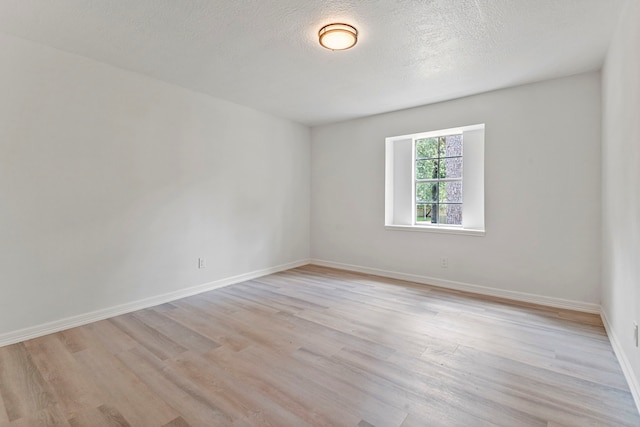 empty room with a textured ceiling and light hardwood / wood-style flooring