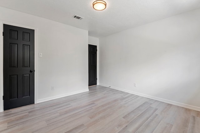 spare room featuring a textured ceiling and light wood-type flooring