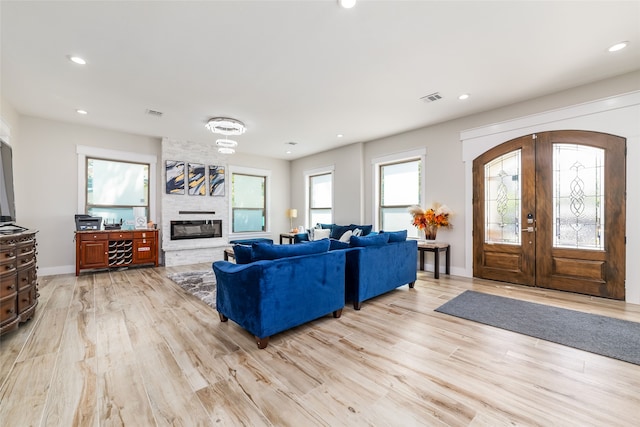 living room featuring a fireplace, light wood-type flooring, and a healthy amount of sunlight