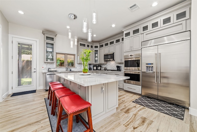 kitchen with gray cabinets, a center island, tasteful backsplash, and stainless steel appliances