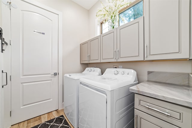 clothes washing area with separate washer and dryer, cabinets, and light hardwood / wood-style flooring