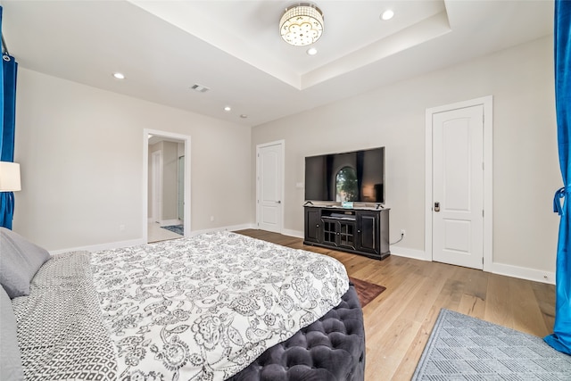 bedroom featuring light hardwood / wood-style floors and a raised ceiling