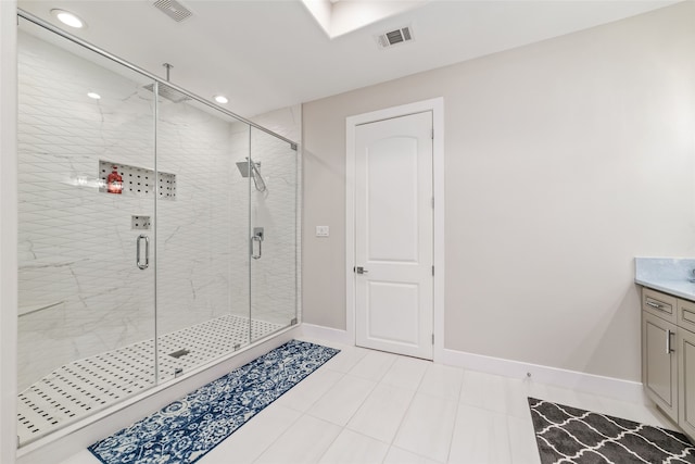 bathroom with a shower with door, vanity, and tile patterned flooring