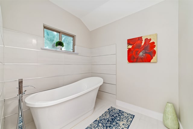 bathroom with tile patterned flooring, lofted ceiling, tile walls, and a tub