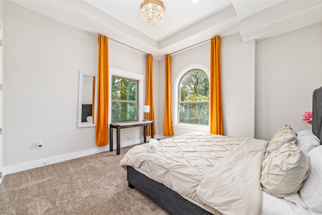 bedroom featuring carpet, a chandelier, and a tray ceiling