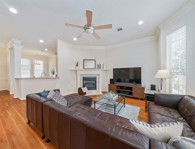 living room with ceiling fan, crown molding, light hardwood / wood-style floors, decorative columns, and sink