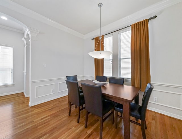 dining space with decorative columns, crown molding, and hardwood / wood-style flooring