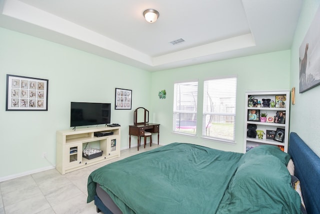 tiled bedroom featuring a tray ceiling