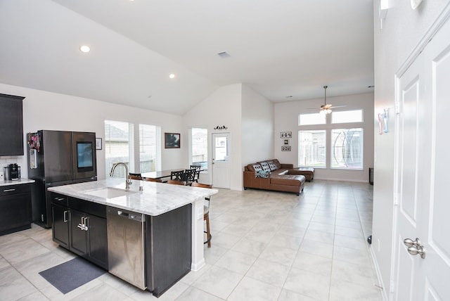 kitchen with a center island with sink, black dishwasher, a healthy amount of sunlight, stainless steel refrigerator, and sink