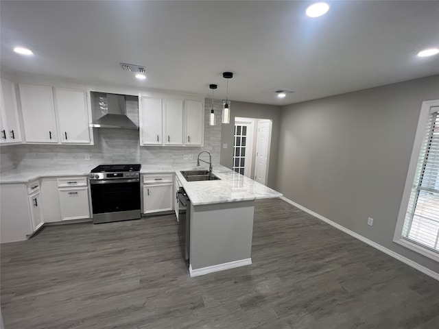 kitchen with stainless steel range with gas stovetop, wall chimney exhaust hood, sink, dark hardwood / wood-style floors, and kitchen peninsula