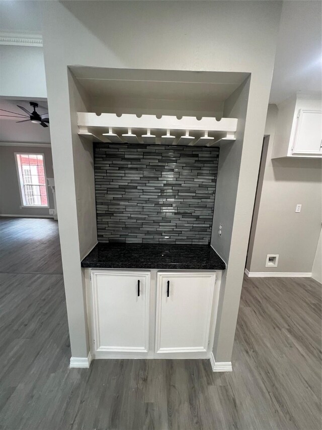 bar with decorative backsplash, ceiling fan, hardwood / wood-style floors, and white cabinets