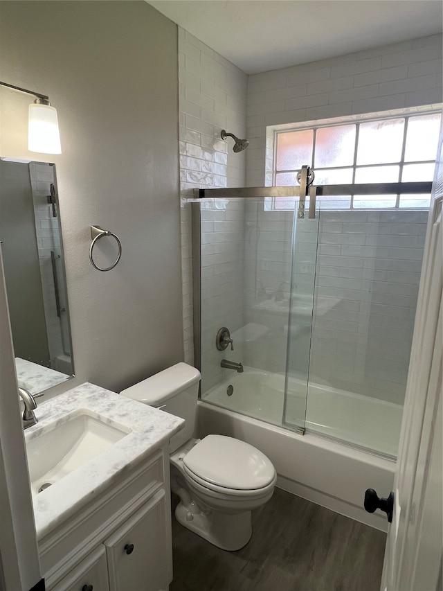 full bathroom with bath / shower combo with glass door, toilet, vanity, and hardwood / wood-style floors