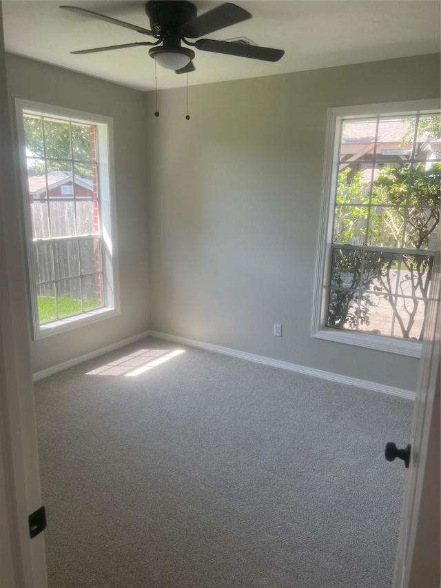 carpeted spare room featuring ceiling fan and a wealth of natural light