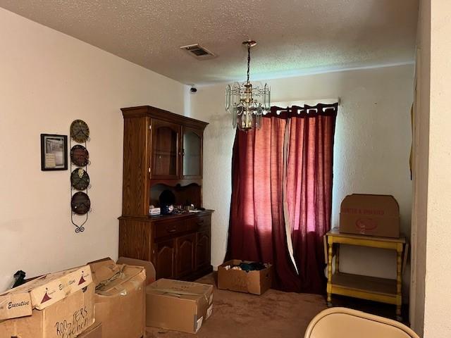 dining area with carpet, a notable chandelier, and a textured ceiling