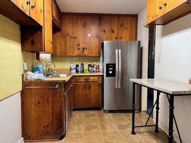 kitchen featuring sink, stainless steel fridge, and tasteful backsplash