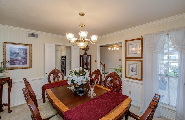 carpeted dining area featuring ceiling fan with notable chandelier and ornamental molding