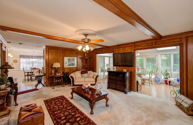 living room featuring a wealth of natural light, ceiling fan, and wooden walls