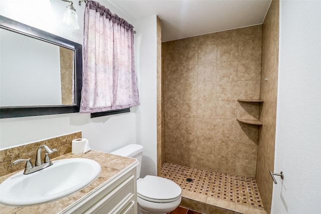 bathroom with tiled shower, vanity, and toilet