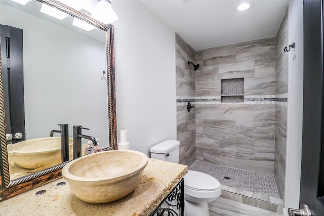 bathroom with vanity, toilet, and tiled shower