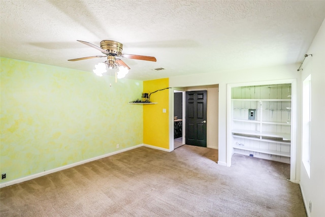 carpeted spare room with ceiling fan and a textured ceiling